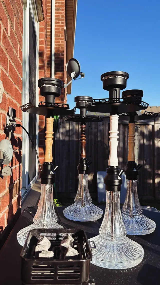 Four hookahs set up outdoors against a brick wall on a clear day