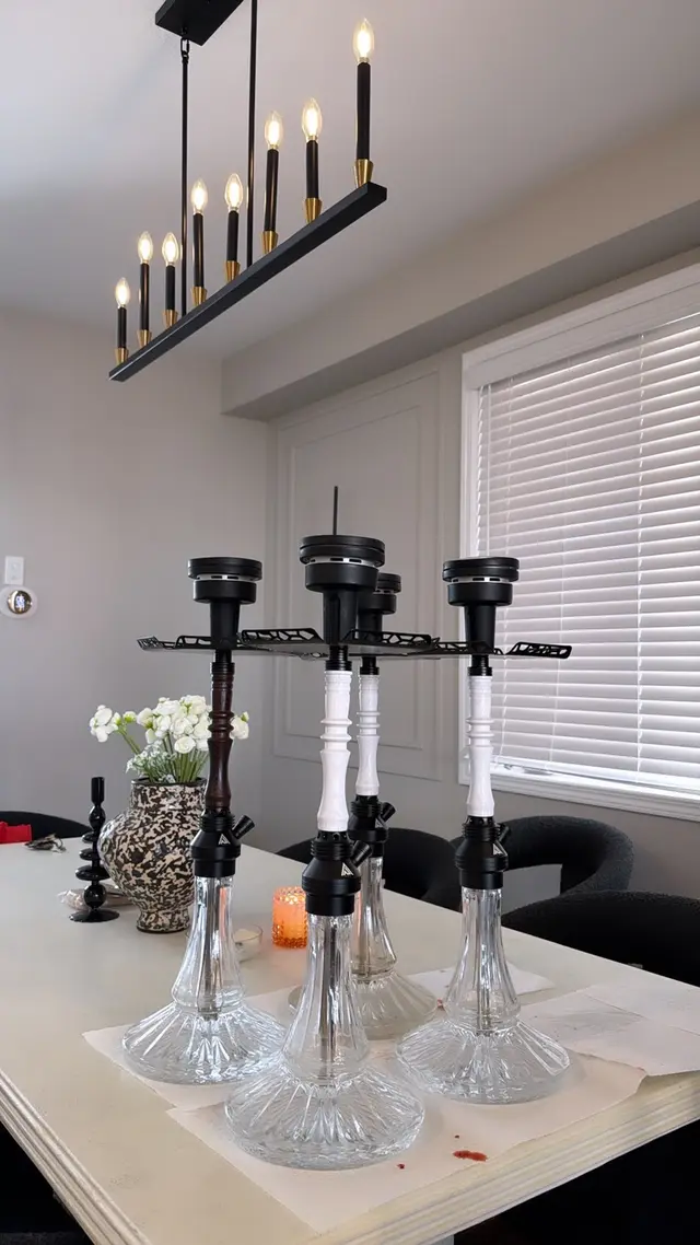 Four hookahs set up on a dining table beneath a candle-bar chandelier