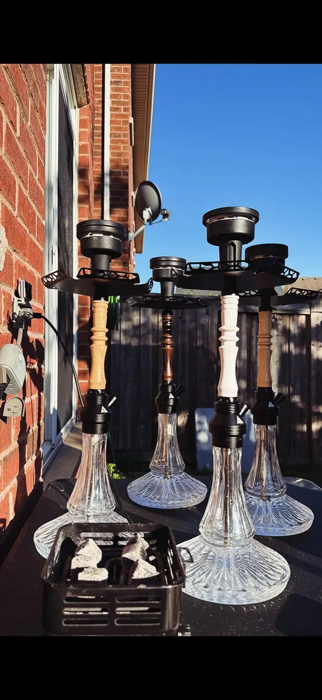 Four hookahs set up outdoors on a sunny day, brick wall behind