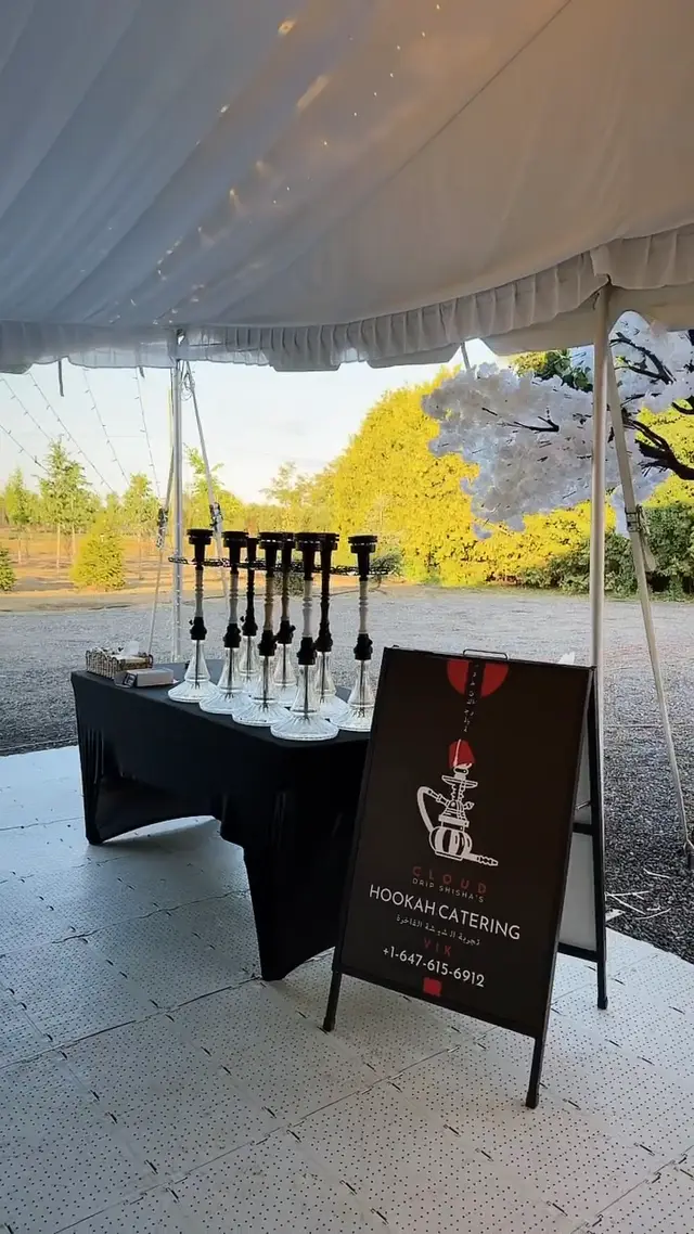 Row of hookahs on a draped table under a garden marquee