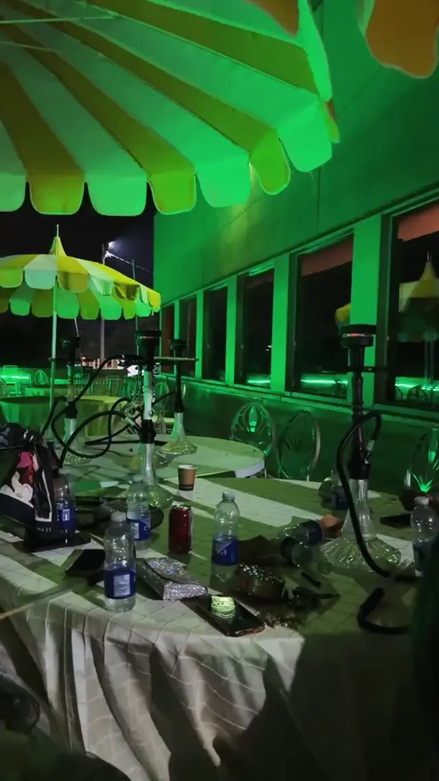 Hookahs set out under a green awning at an outdoor venue