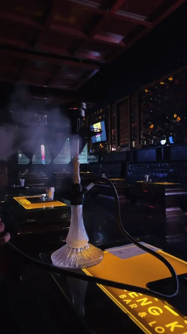 Hookah running on the bar of a low-lit lounge, smoke rolling across the counter