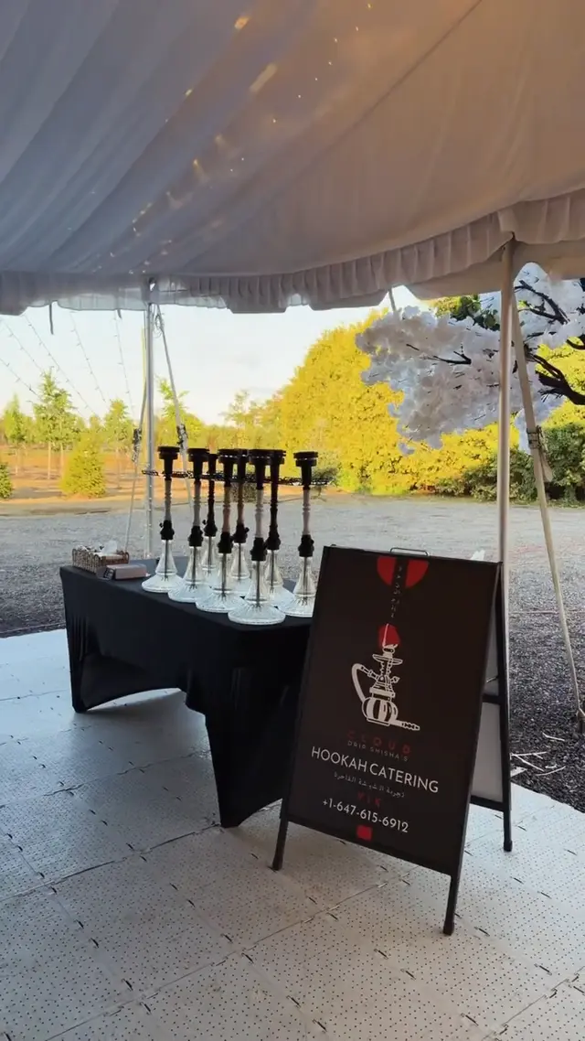 Row of hookahs on a draped table under a garden marquee