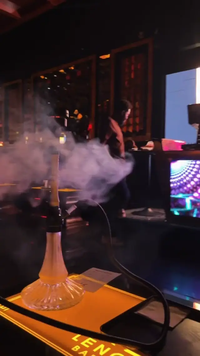 Hookah running on the bar of a low-lit lounge, smoke rolling across the counter